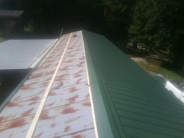Old rusted panels beside newly installed green metal roofing — Wind Damage Roof Repair by Roofing Brothers in Alachua