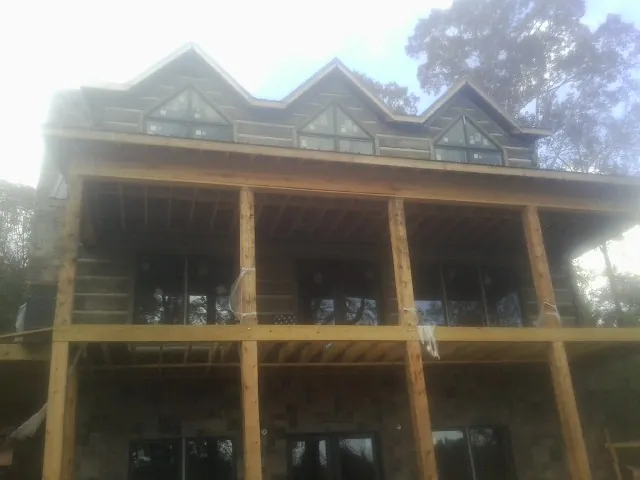 Dormers and porch framing on a large log home under construction — Roof Coating work by our crew in Alachua