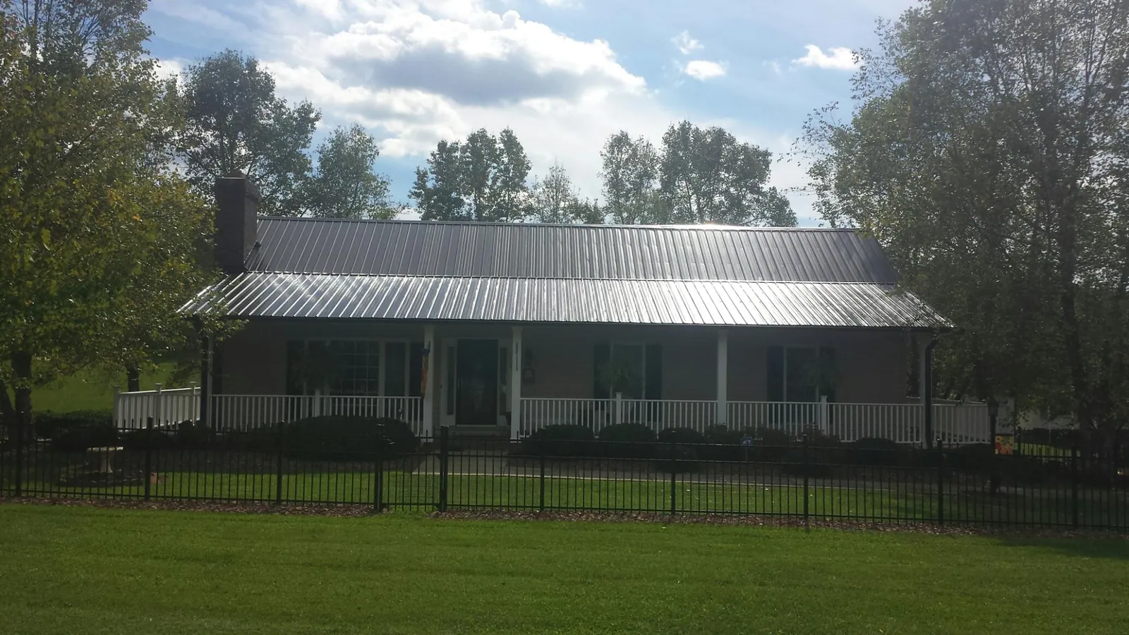 Gray metal roof on a brick ranch with a full width front porch — Gutter Guard Installation work by our crew in Alachua