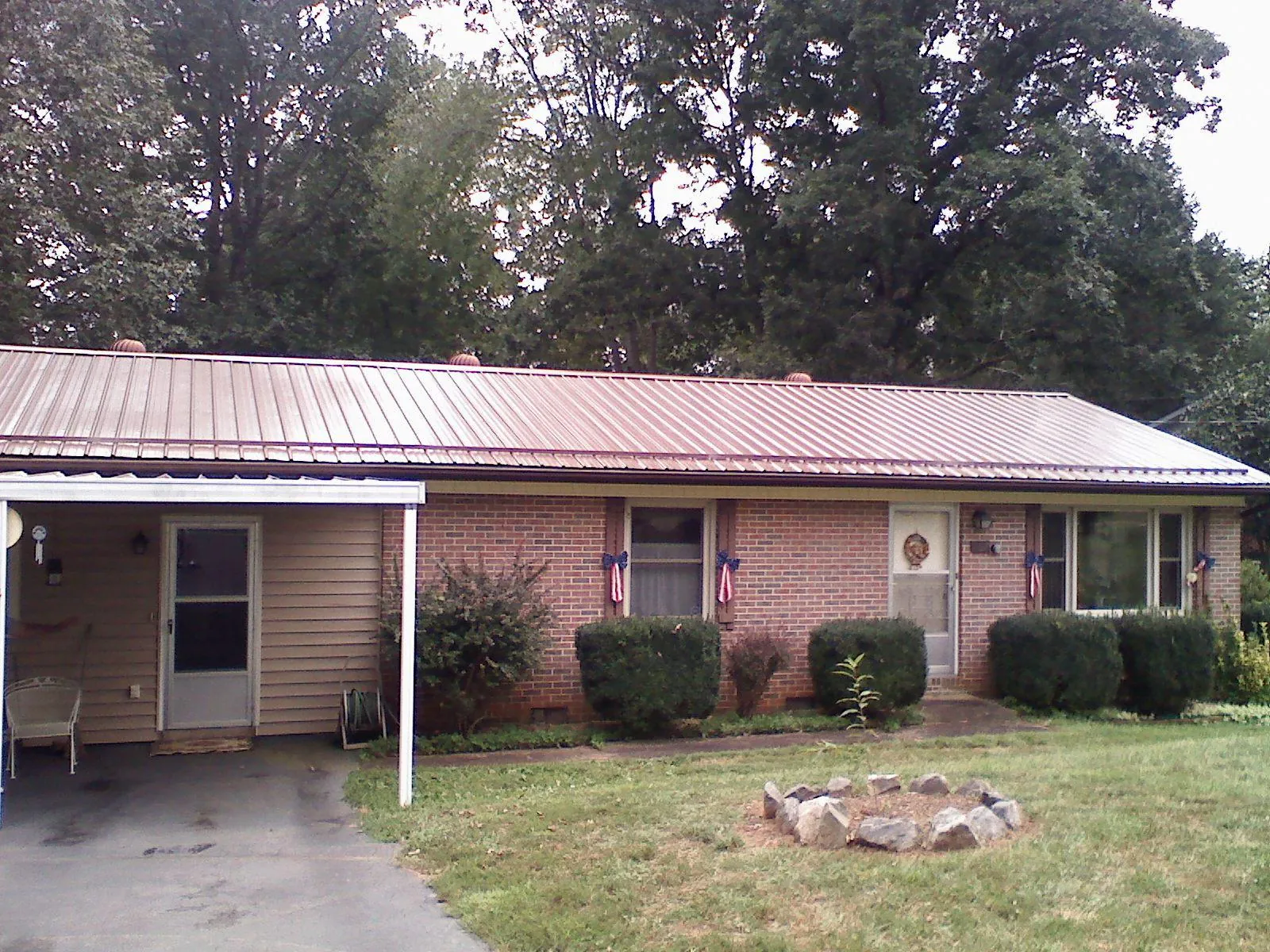 Bronze metal roof and carport on a brick ranch home — Roof Repair work by our crew in Alachua