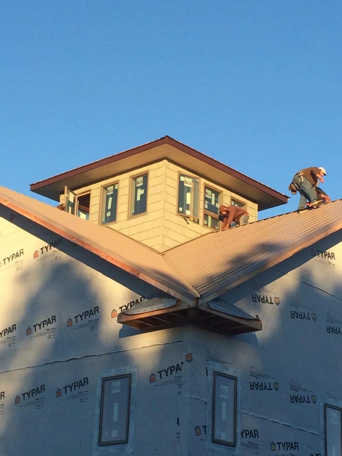 Roofers working around a rooftop cupola on a new metal roof at sunset — Roof Waterproofing in Alachua by Roofing Brothers